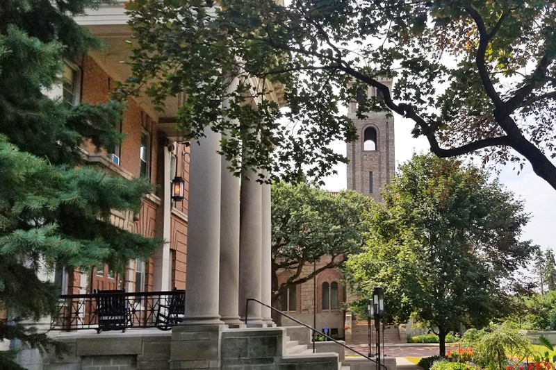Shot of the front of Derham Hall through tree foilage.