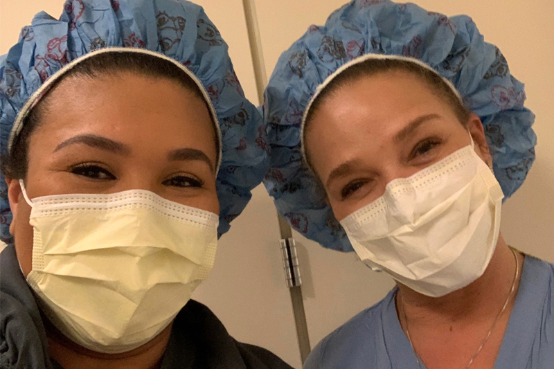 In scrubs and facemasks, Danyel (Downs) Braziel ’19, RN, CCRN, PHN, and Irita (Downs) King ’93, RN, CRNI, VA-BC