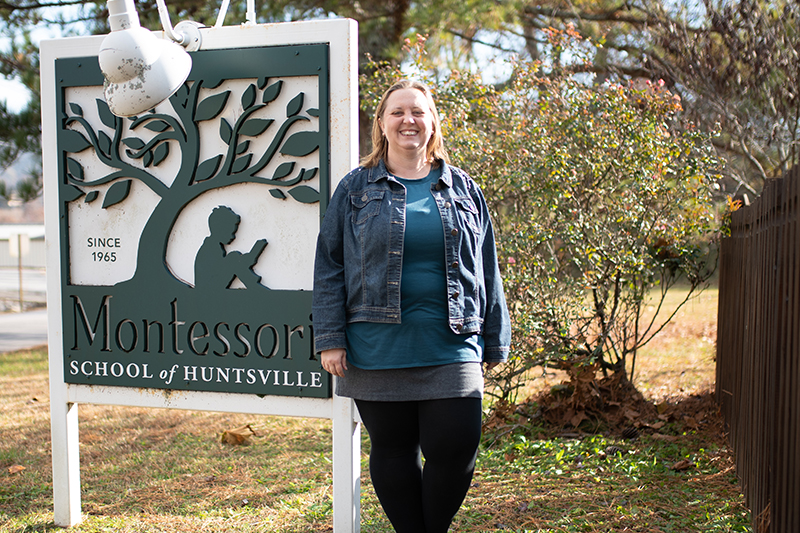 Rebekah Spooner ’23 in front of a sign for her Montessori school