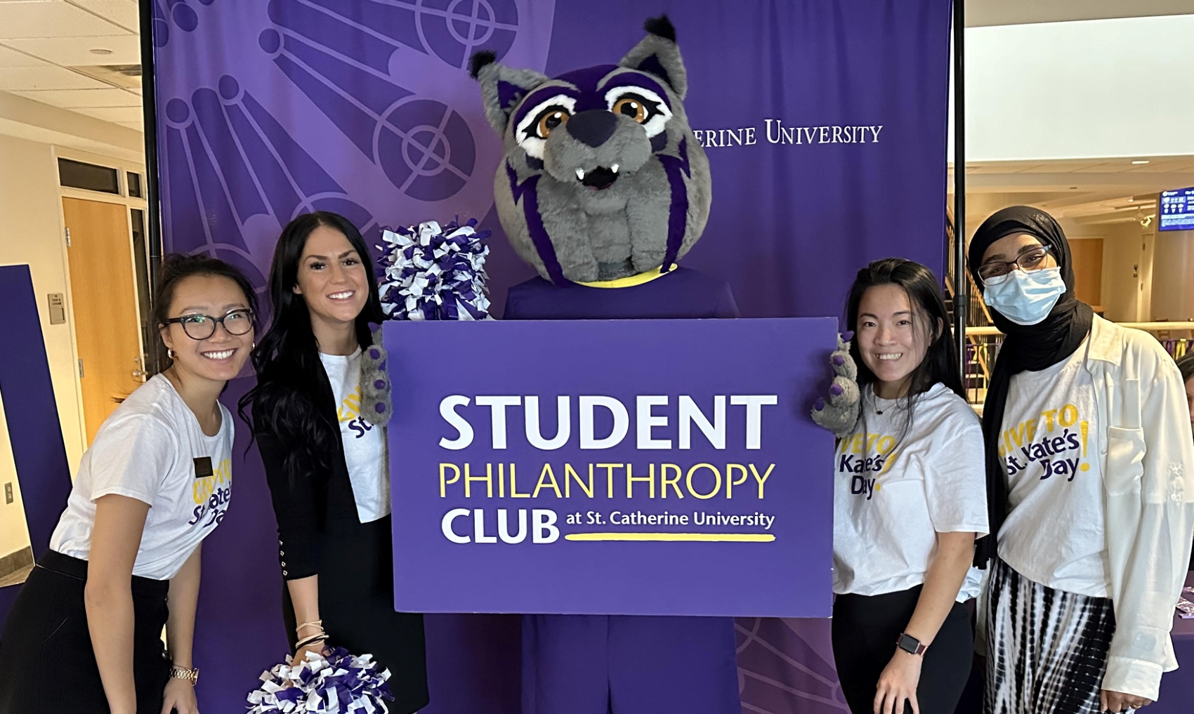 Students and staff gather with the Wildcat mascot and a sign that reads, "Student Philanthropy Club"