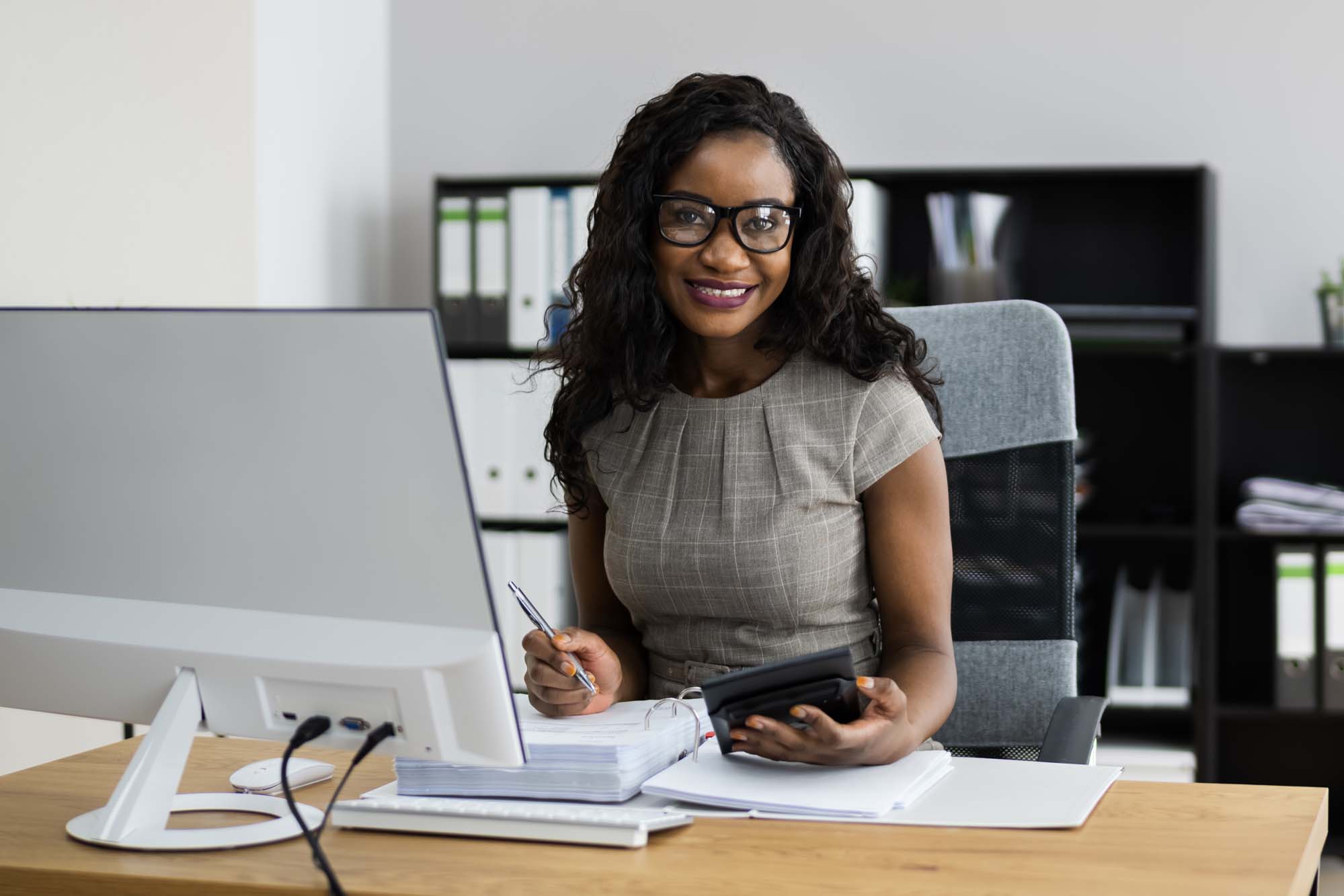 A smiling Accounting graduate working at a desk in an office