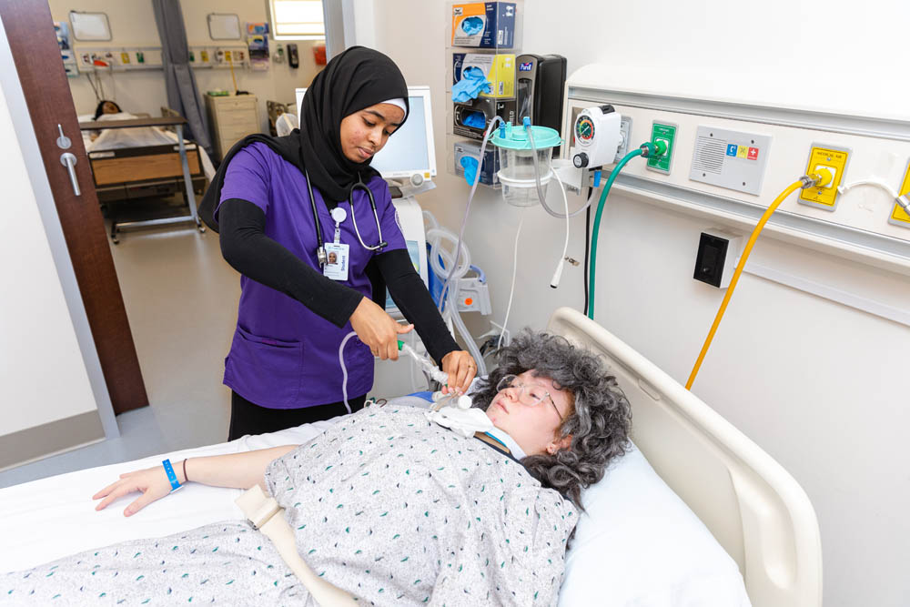 A Respiratory Care student practicing caring for a mannequin in a simulated medical environment.
