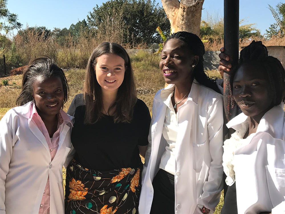Public health student posing with kids in Africa