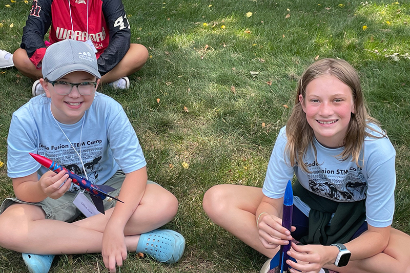 two campers sitting and showing off their rockets