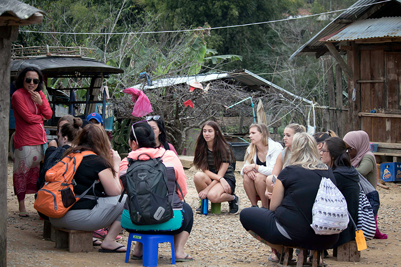 Students studying abroad sitting in a circle in a village