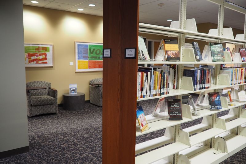 A sitting area in the library partially blocked by a library stack with books on it.