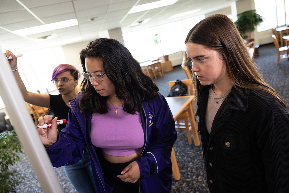 Three students collaborating on whiteboard