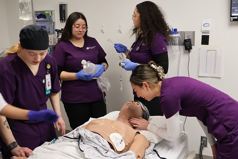 Four nursing students working together on a patient simulation