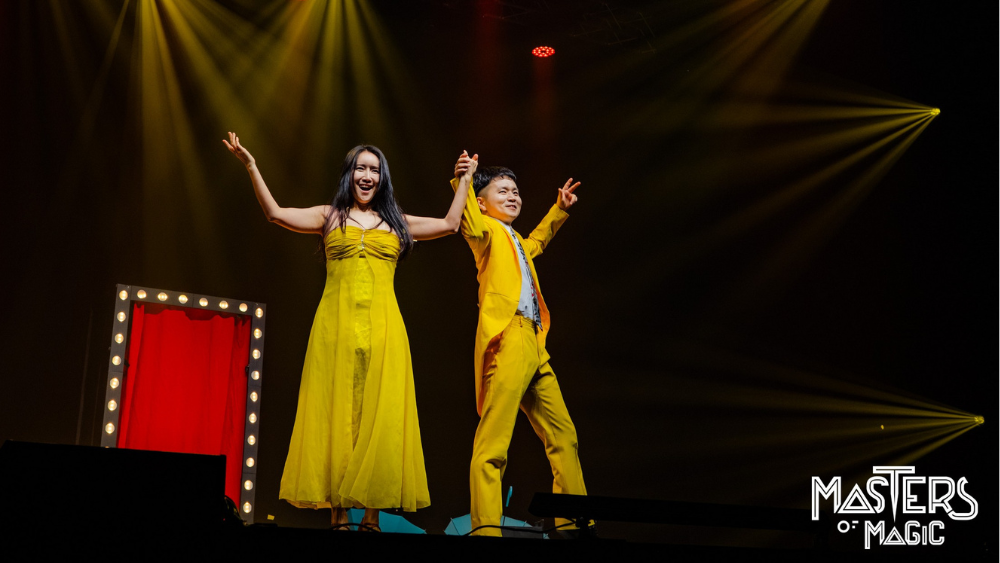 Two magicians on stage in yellow costumes