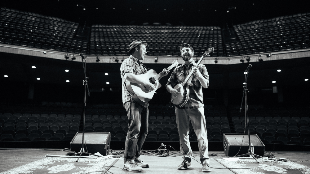 Two men playing a guitar and banjo on stage