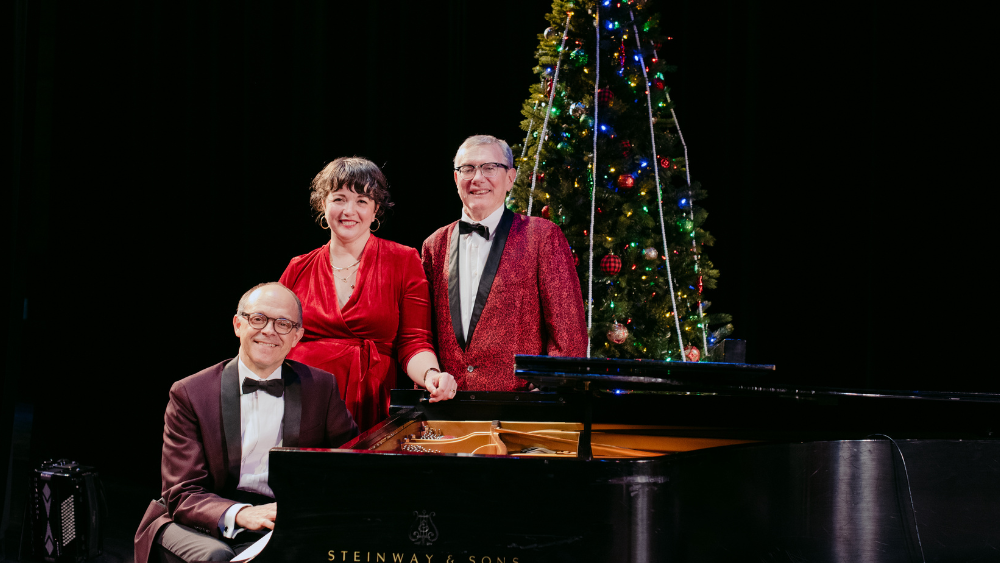 Kevin Kling and Friends sitting at the piano with the Christmas tree in the background
