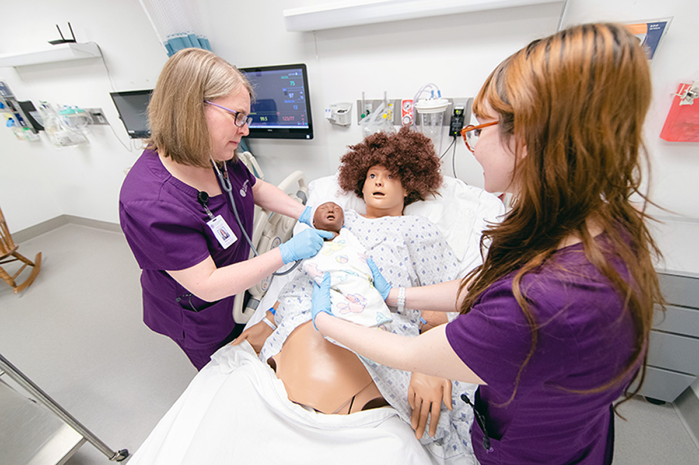 two nursing students working on simulation dummy