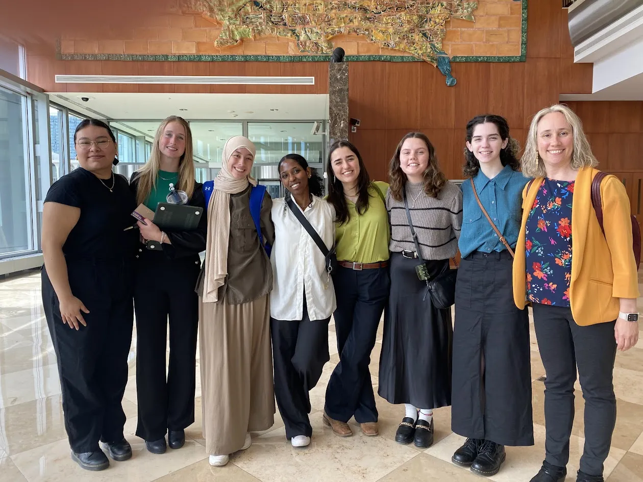 7 students and one professor standing at the entrance to the Minneapolis Federal Reserve Bank