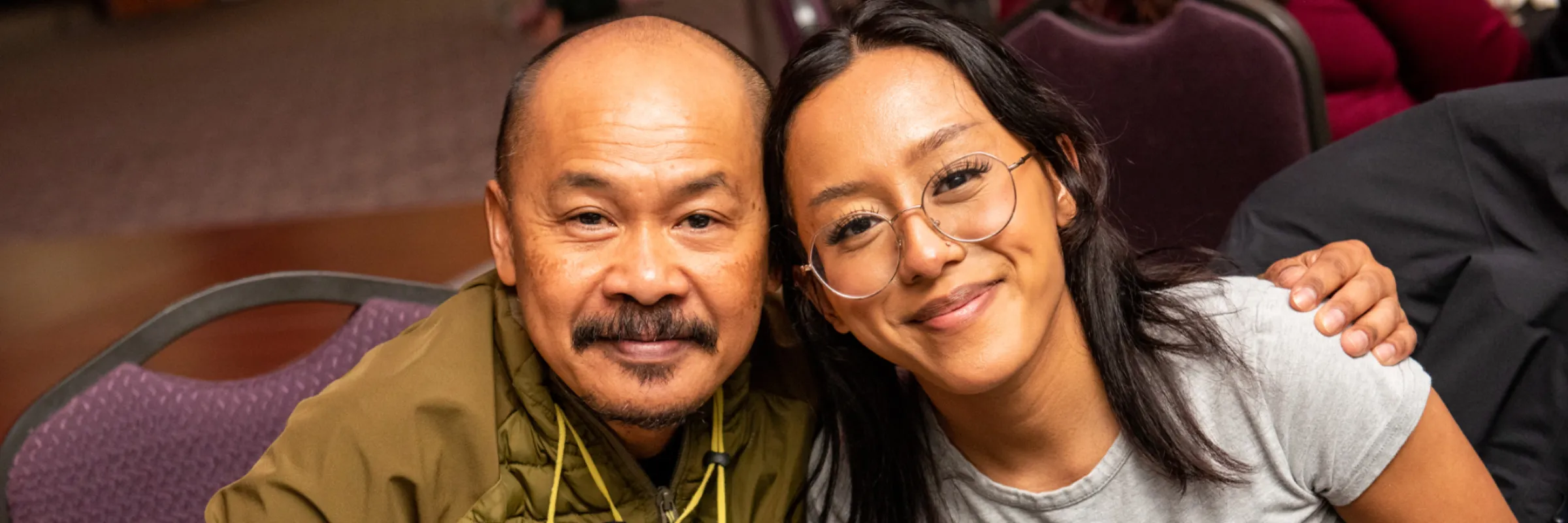 A father and daughter hugging and looking at the camera