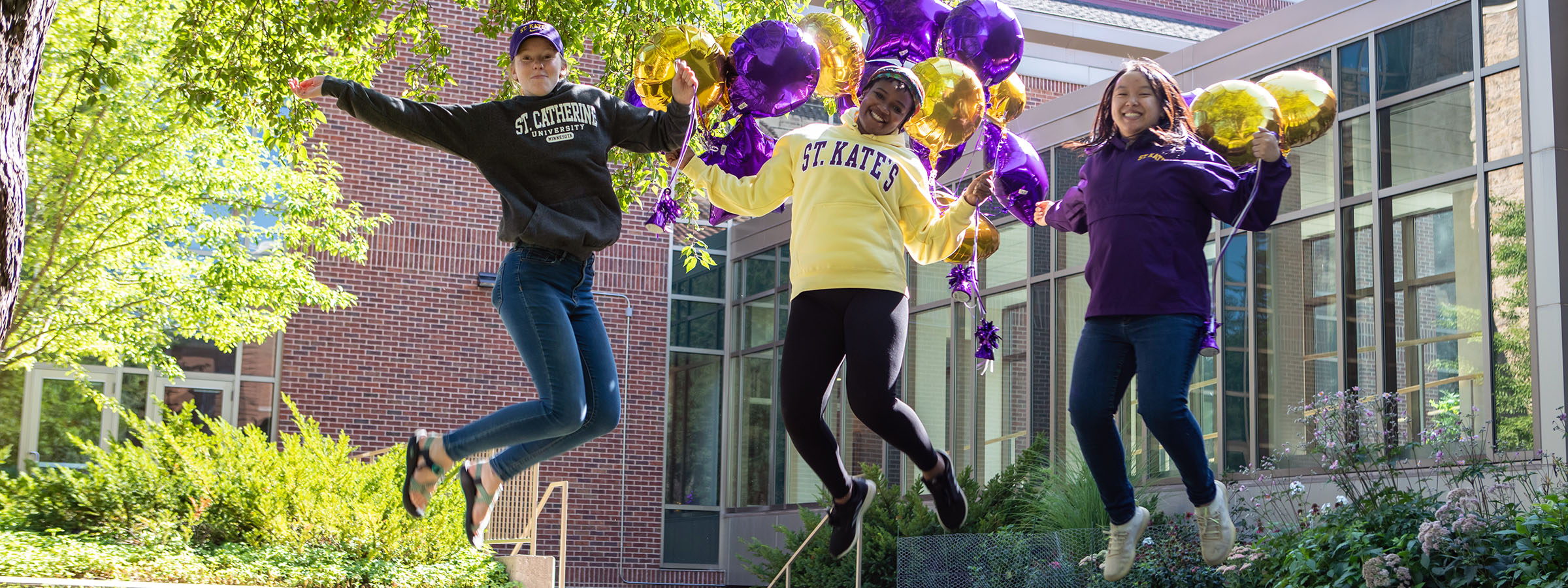three students jumping in the air in celebration