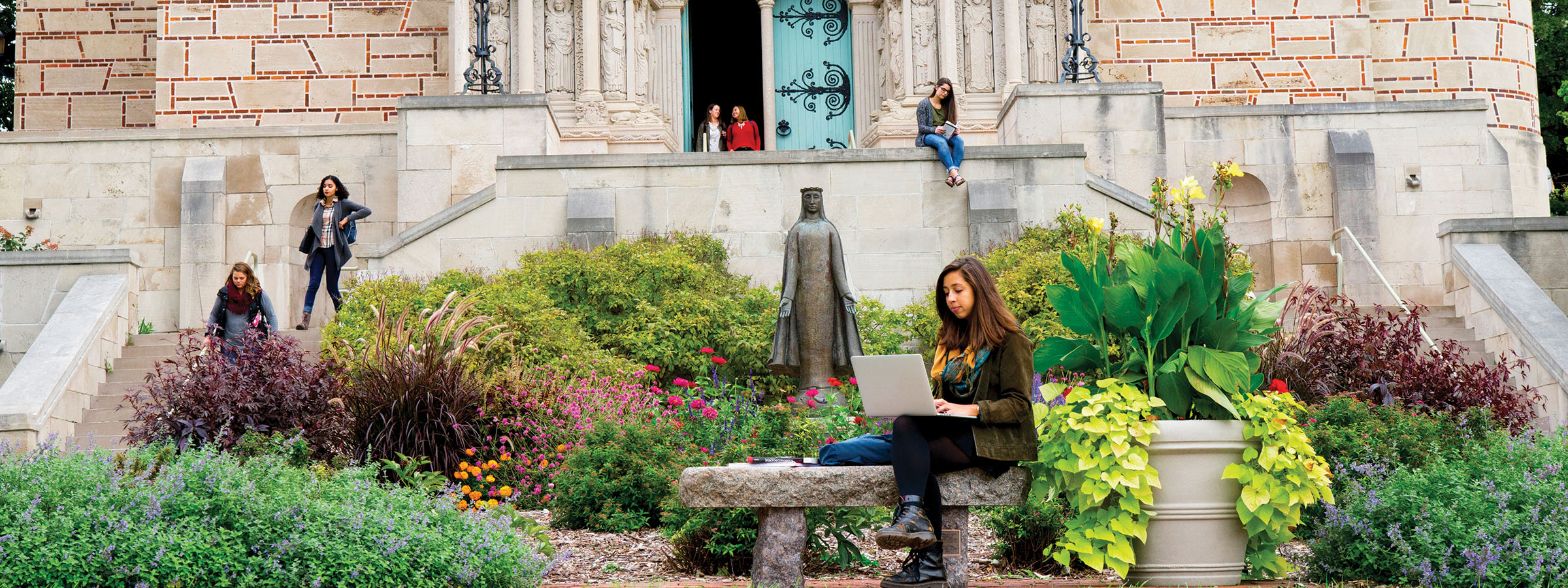 Women commuting and reading outside in front of campus chapel