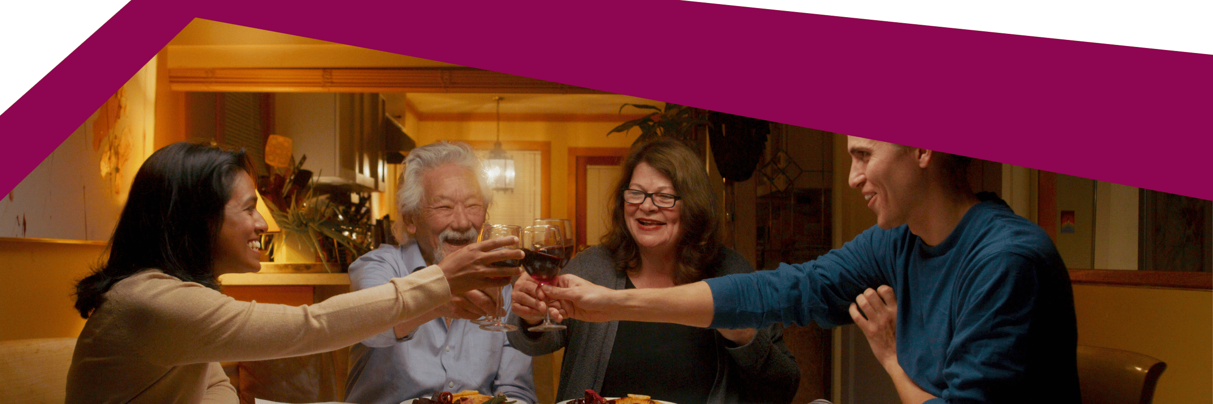 four family members sitting around a dinner table smiling