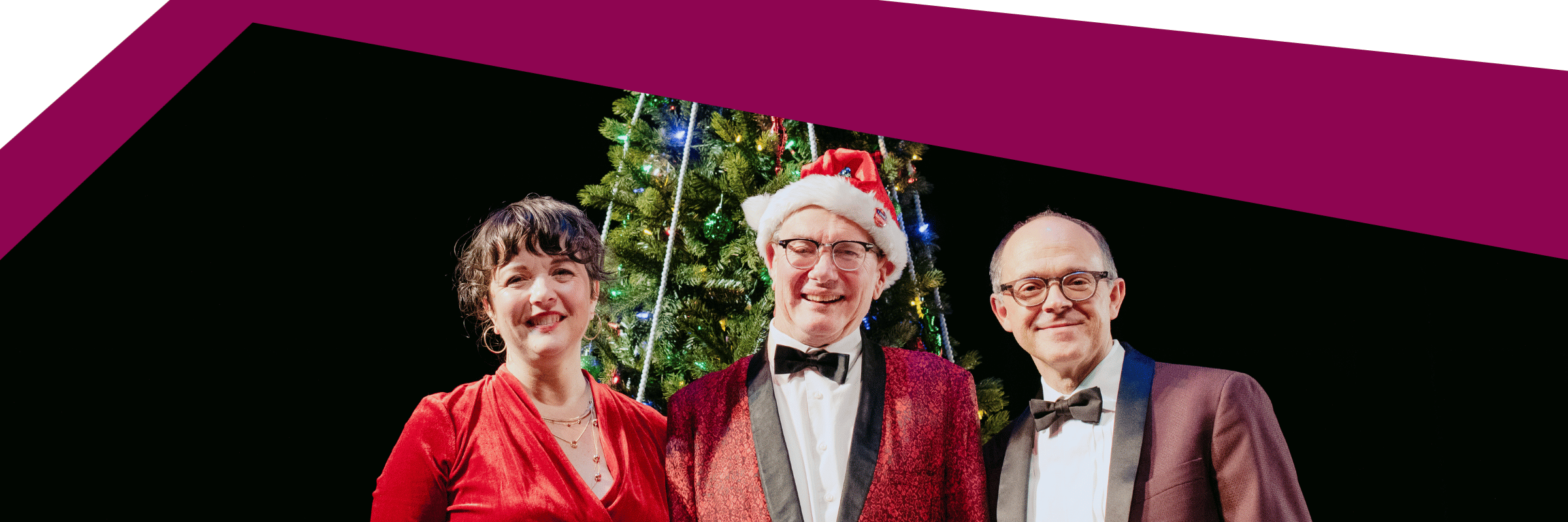 three performers standing in front of a Christmas tree