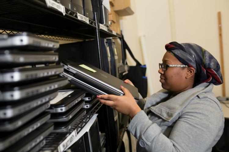 Student worker, working in technology center putting laptops into storage