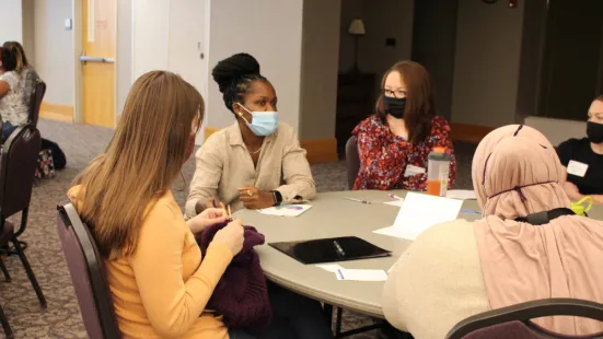 Students seated at a table discuss during IPE forum