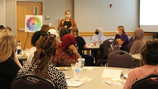 Standing speaker addresses students seated at tables