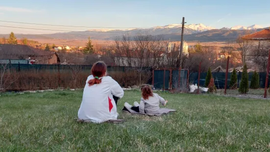 Two girls sit on the grass and stare at the landscape