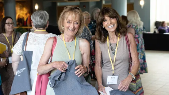 Smiling alumni with matching complimentary tote bags pose for a photo at Reunion