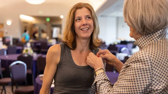 President Roloff '76 attaches a pin to an alumna's shirt