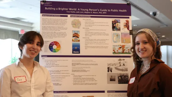 Two students stand in front of their research poster. 