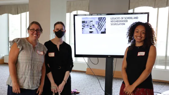 Student and faculty researchers stand in front of a screen showing a research presentation.