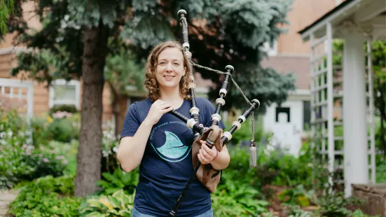 Katie stands outside holding her bagpipes