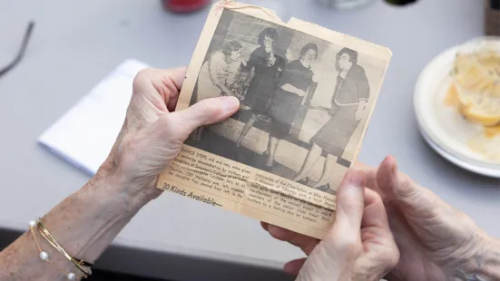 Two hands hold an old, yellowed photograph. 