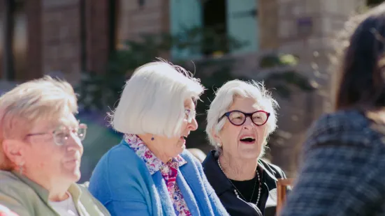 Three women with white hair smile and laugh.