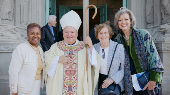 Three women pose on either side of the bishop.