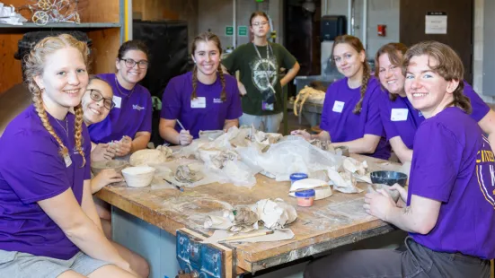 A group of Citizen Katie volunteers smiling at the camera while sitting around a square table.