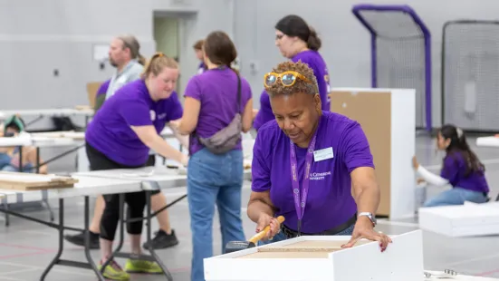 President Marcheta P. Evans in the foreground assembling a dresser. There are more Citizen Katie volunteers working in the background.