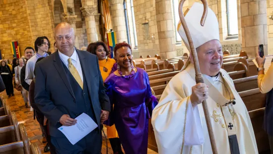 President Evans and her husband walk through the Chapel behind Archbishop Hebda
