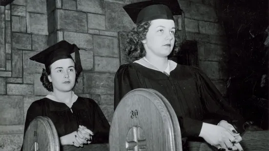 Two students in the chapel pews in caps and gowns.