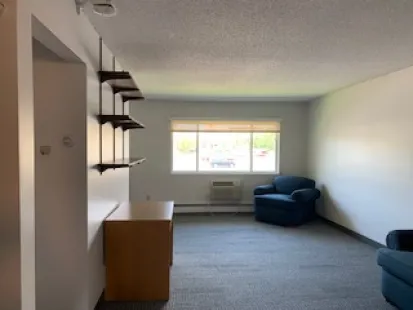 Alberta Living Room with pre-furnished items including a tv stand, shelving, and chairs.