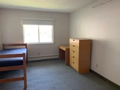 Bedroom in the Alberta and Georgia apartments already furnished with a bed, desk, and dresser.