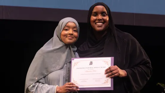Two students smile and hold a certificate. 
