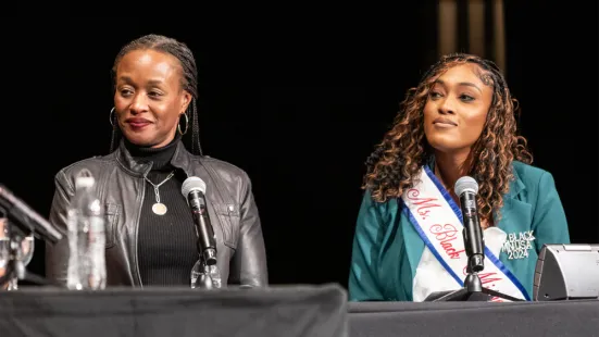 Two women sit at a table with microphones.