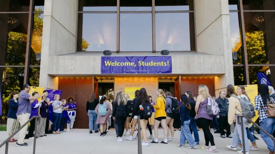 A crowd of people enter a building with a sign that reads "Welcome, Students!"