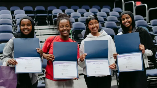 Four students holding certificates for completion of the KLI business camp.