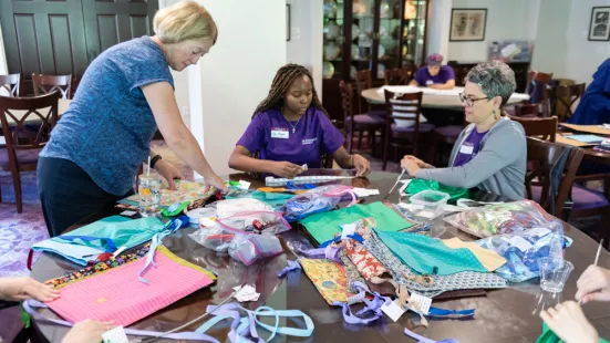 Three women work at a table measuring fabric.