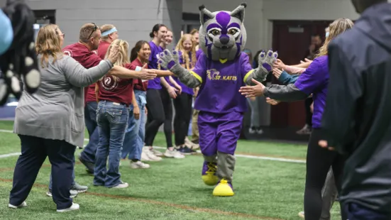 The Katie Cat mascot walks through a tunnel of high fives.