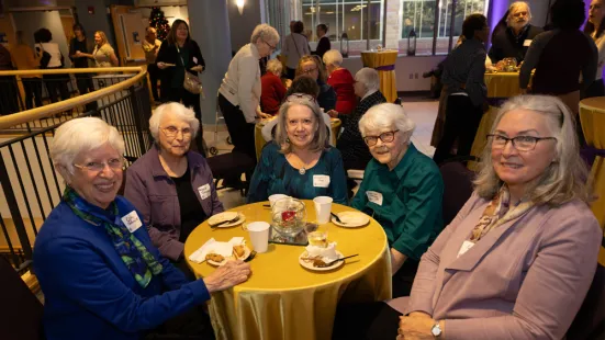 A group of women sit around a table at the Feast of Saint Catherine reception.