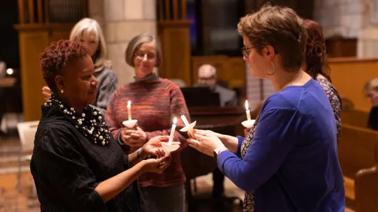 Two people lift their candles to each other during the Feast of Saint Catherine prayer service.