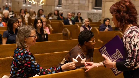 Attendees at the prayer service hold lit candles together.