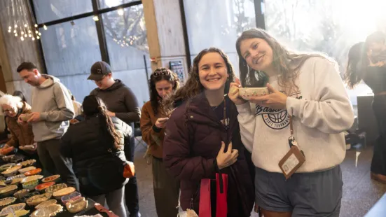 Two students pose with a ceramic bowl at the Empty Bowls event